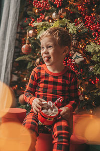 Portrait of cute girl playing with christmas tree at home