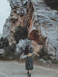 Portrait of woman in sexy back dress standing in front of rock mountain 