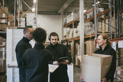 Male and female manual workers discussing during meeting in logistics warehouse