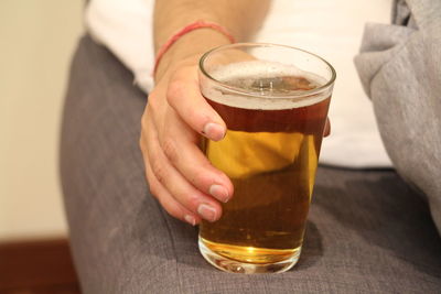 Close-up of hand holding beer glass