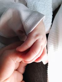 Cropped image of baby holding parent hand