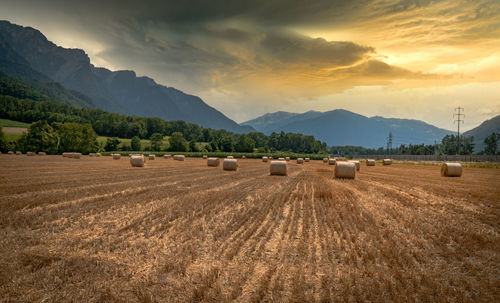 Hay bales on field against sky during sunset