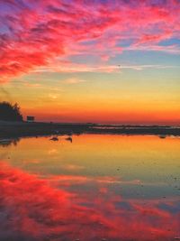 Scenic view of lake against dramatic sky during sunset