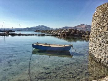 Boats moored at harbor against clear sky