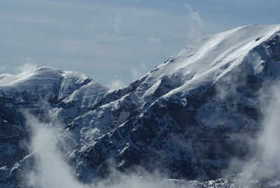 Scenic view of snow covered mountains against cloudy sky