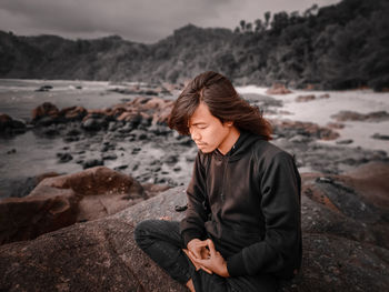 Young woman sitting on rock at beach