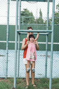 Portrait of a smiling girl standing against fence