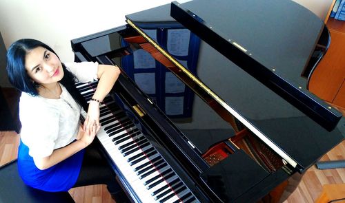 Smiling young woman playing piano