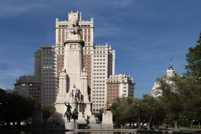 Statue in city against sky