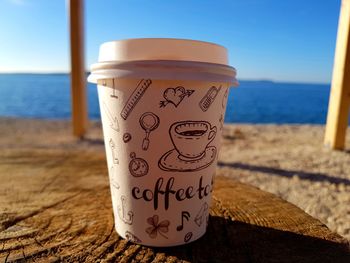 Close-up of coffee in disposable cup on table at beach