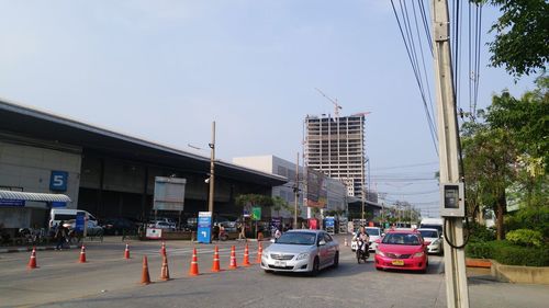 Cars on city street against sky