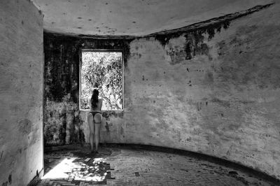 Rear view of young woman standing in abandoned building