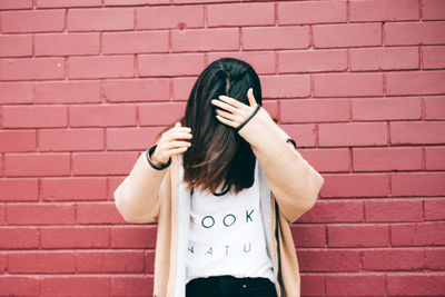 Woman standing against brick wall