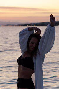 Woman standing at beach during sunset