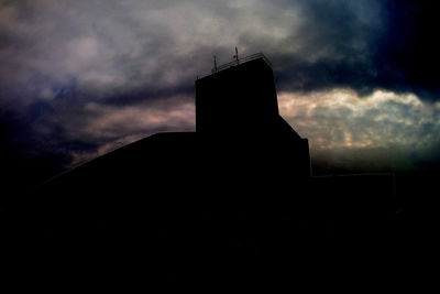 Low angle view of silhouette building against cloudy sky