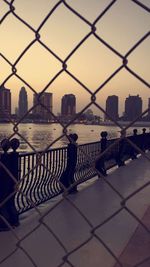 View of city buildings seen through chainlink fence