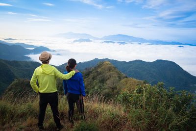 Rear view of couple standing on mountain against sky