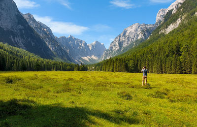 Photographer in the middle of green valley surrounded by mountains.