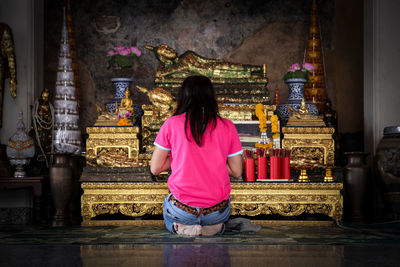 Rear view of woman walking in temple against building