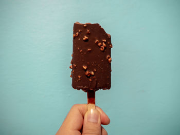 Close-up of hand holding ice cream cone against blue sky