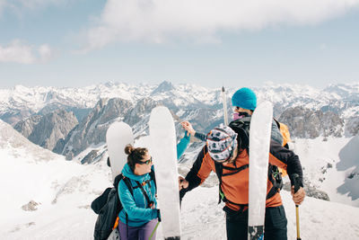 Sportspeople with skis and rucksacks interacting on snowy mountain on pico aunamendi of pyrenees in navarre spain