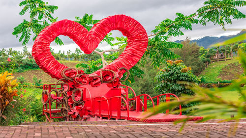 Red heart shape on tree against sky