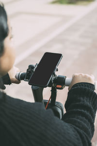 Closed view of smart phone, young latina woman, driving electric scooter