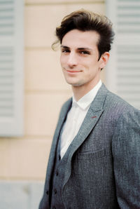 Portrait of young man standing against wall