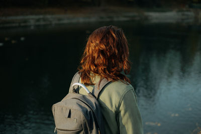 Rear view of woman looking at lake during sunset 