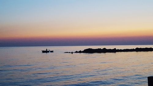 Silhouette boats sailing in sea against clear sky during sunset