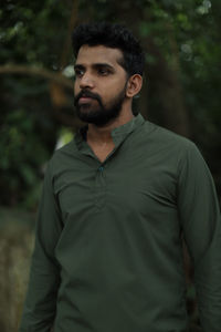 Young man standing against trees