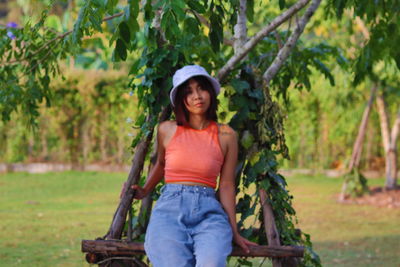 Portrait of happy girl sitting on tree against plants
