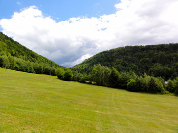 Scenic view of grassy field against cloudy sky