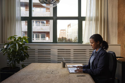 Side view of young man sitting at home