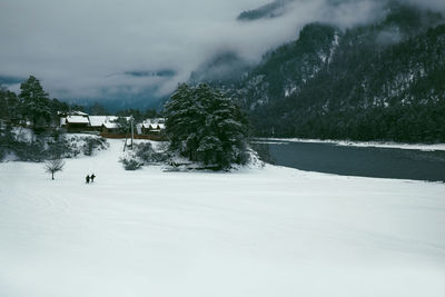 Winter landscape with a village in the mountains on the bank of a mountain river