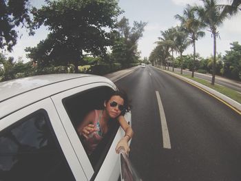 Young woman photographing with selfie stick while sitting in car