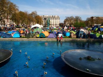 People by swimming pool in city against sky