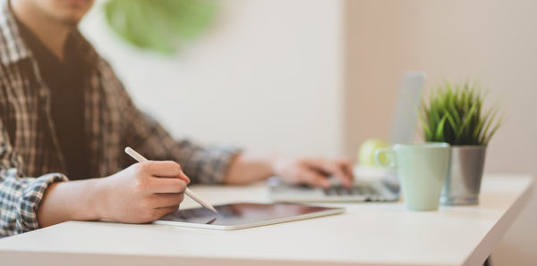 Midsection of businessman using digital tablet on desk in office