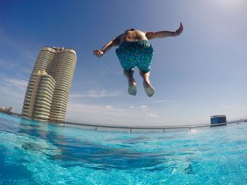 Full length of shirtless man jumping in infinity pool