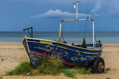 Boat moored on beach against sky