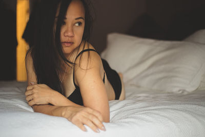 Portrait of young woman lying on bed
