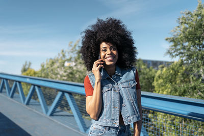 Portrait of a young black woman with a mobile phone at the bridge