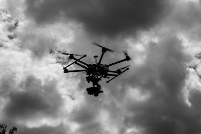 Low angle view of drone against cloudy sky