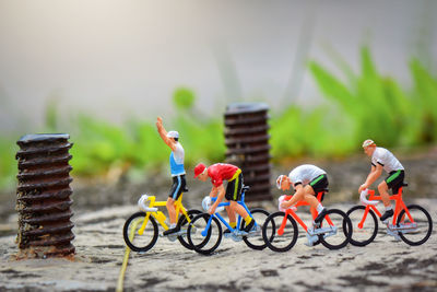 Close-up of male figurines riding bicycles on footpath