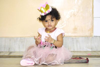 Portrait of cute girl sitting on floor at home