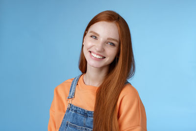 Redhead woman smiling against blue background