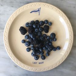 Directly above shot of blueberries and blackberries in plate on floor
