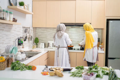 Rear view of women standing in kitchen at home