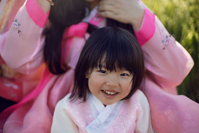 Korean national children pink costume on a four year old girl standing in a field with grass