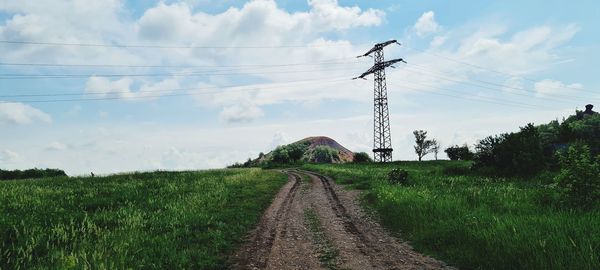 Electricity pylon on field against sky
